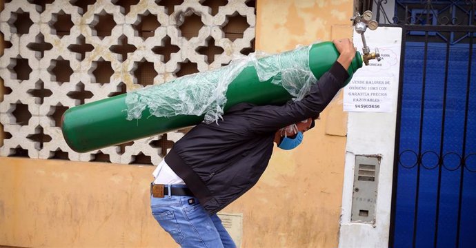 Un hombre carga con una bomba de oxígeno tras haberla rellenado por las calles de Lima. El oxígeno se ha convertido en un bien preciado en Perú debido a su escasez, que a su vez ha sido apovechado por el sector para subir su precio.