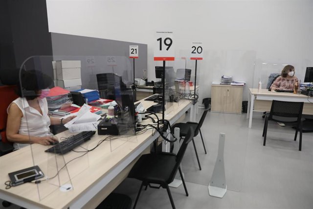 Dos trabajadoras de una Oficina de Empleo de la Comunidad de Madrid protegidas con mascarilla y con una pantalla separadora