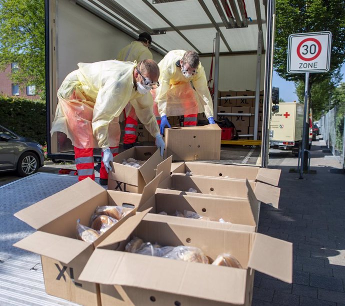 Voluntarios de la Cruz Roja reparten pan en varios bloques de apartamentos en los que viven trabajadores del grupo Toennies en cuarentena