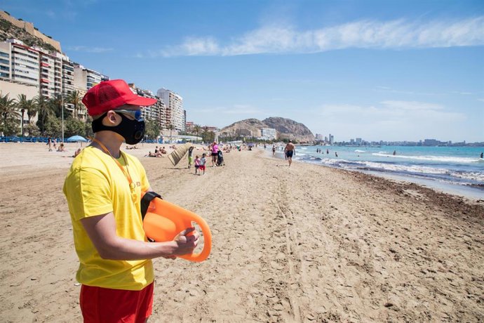 Un socorrista protegido con mascarilla vigila la Playa del Postiguet durante el primer día de la Fase 2, cuando se puede acceder a las playas de la misma provincia, isla o unidad territorial de referencia establecida en el plan de desescalada, y cuando 