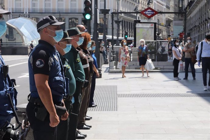 Miembros de distintos cuerpos de seguridad, como la Guardia Civil y la Policía Municipal de Madrid, guardan un minuto de silencio en memoria por los fallecidos por el COVID-19 en la Puerta de Sol.