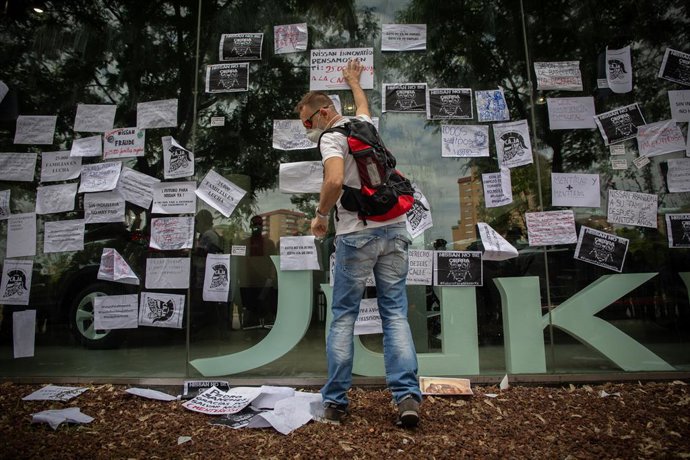 Un trabajador de Nissan cuelga carteles de protesta en un concesionario en Barcelona. 