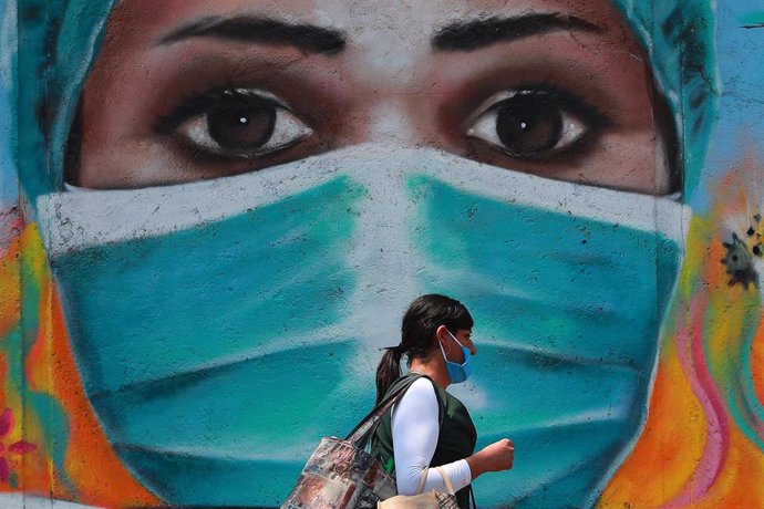 Una mujer camina por las calles de Ciudad de México frente a un mural pintado en homenaje a los trabajadores de la salud durante la pandemia de la COVID-19.