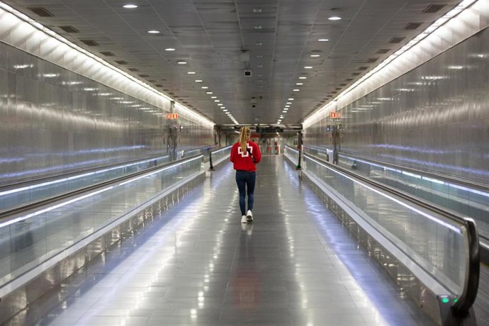 Una voluntaria de Cruz Roja camina por la estación catalana de Diagonal donde están repartiendo mascarillas con motivo de la reactivación de la actividad laboral no esencial en Cataluña en las empresas cuyos empleados no puedan teletrabajar, cuando se c