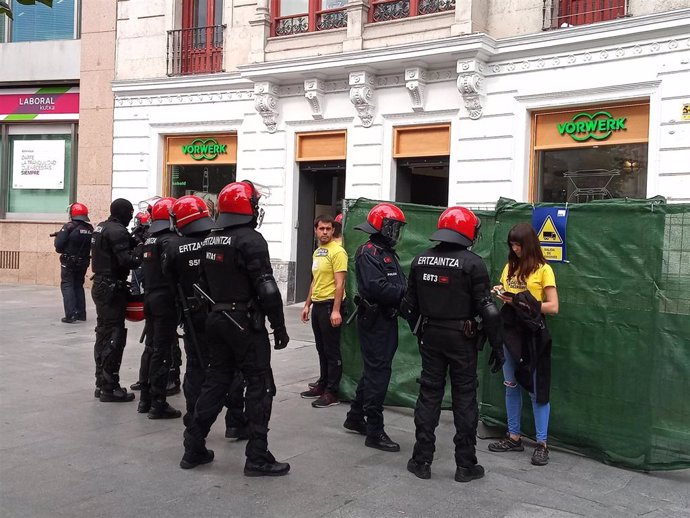 Ertzainas identifican a miembros de Ernai por obstaculizar la entrada a una sucursal de la Caixa en Bilbao.