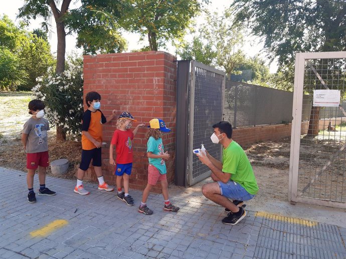 Diversos nens i nenes fan cua perqu un monitor els prengui la temperatura, com a mesura contra el contagi de coronavirus, en el primer dia de colnies d'estiu a Barcelona, el dilluns 22 de juny del 2020