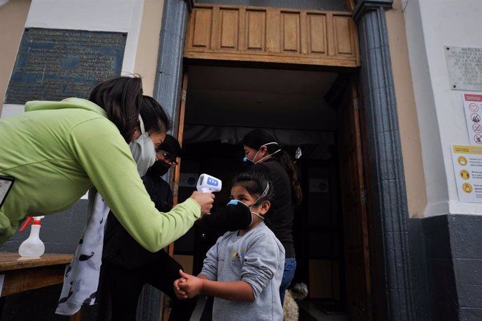 Una mujer toma la temperatura a una niña delante de una iglesia en Quito