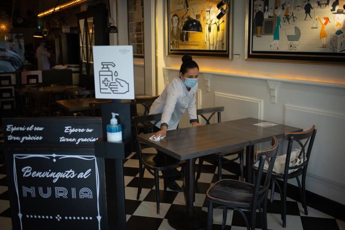 Una camarera limpia una mesa del histórico local barcelonés Núria.
