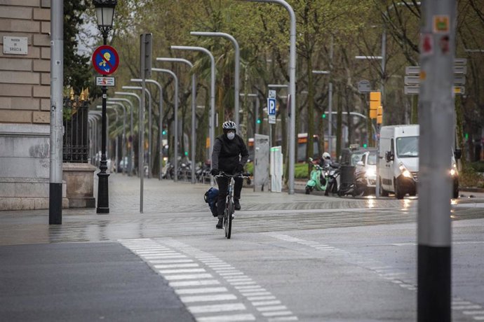 Una persona monta en bicicleta y se protege con una mascarilla durante el segundo día laborable del estado de alarma por el coronavirus, en Barcelona (España), a 17 de marzo de 2020.