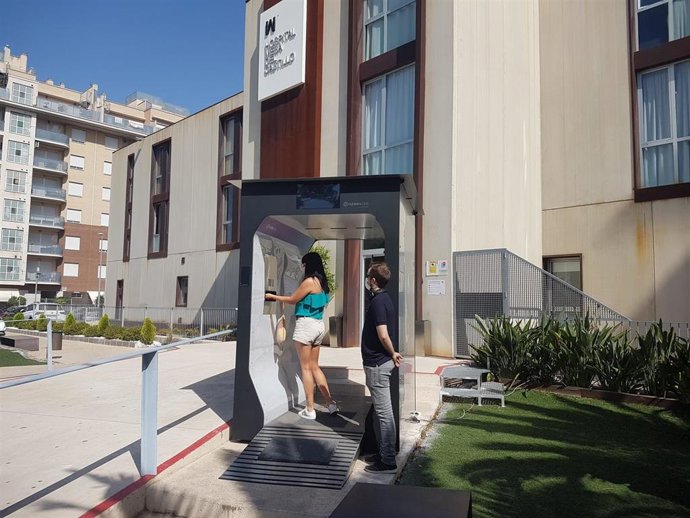Una mujer pasa por el túnel de control y desinfección instalado en el Hospital Mesa del Castillo, en Murcia, por la empresa MaskGreen