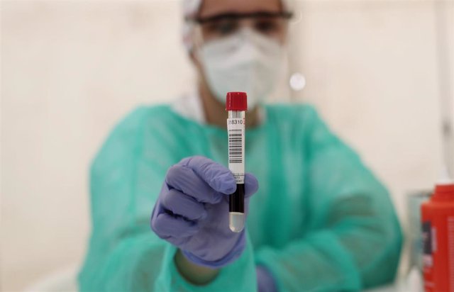 Un sanitario muestra un tubo de ensayo con muestras de un paciente
