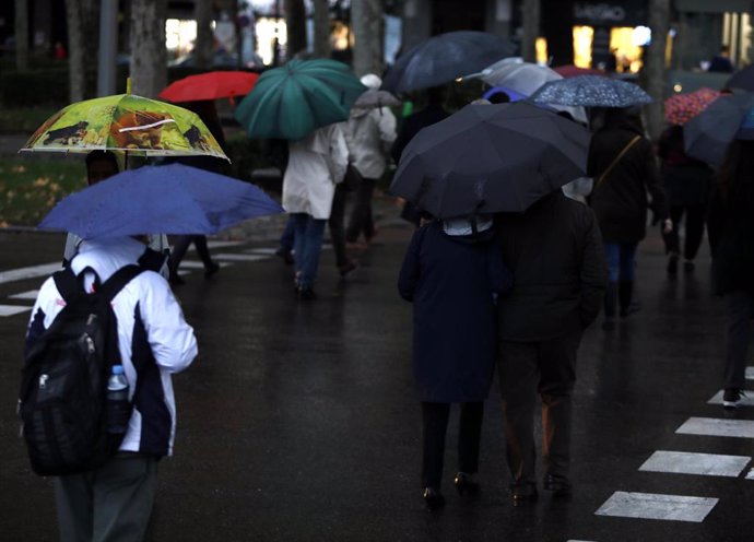 Imagen de recurso de varias personas con paraguas en Madrid