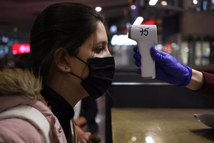 Una ciudadana colombiana se toma la temperatura en el aeropuerto de Santiago, Chile.
