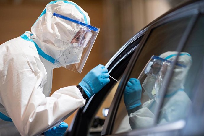 Un militar con traje de protección toma muestras a un conductor para una prueba de coronavirus en el distrito de Guetersloh, donde se sitúa el brote del matadero de Toennies