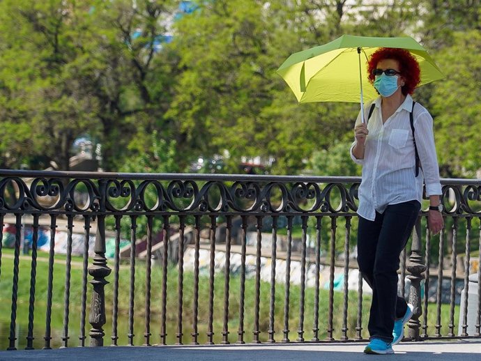 Mujer pasea con un  paraguas amarillo