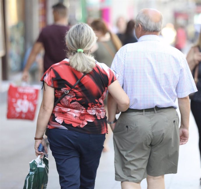 Un pareja de jubilados pasea del brazo.