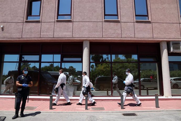 Agentes de la Policía Nacional equipados con Equipos de Protección Individual (EPI), custodian a contagiados de COVID-19 en una de las sede de Cruz Roja en Málaga, (Andalucía, España), a 25 de junio de 2020.
