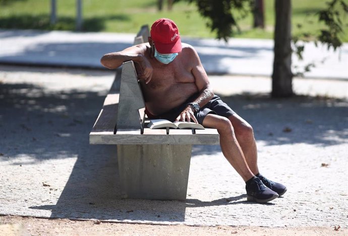 Un hombre lee un libro en un parque parque una jornada con calor, una imagen de arcvhio.