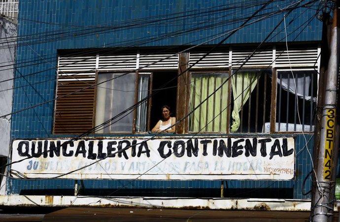 Una mujer mira a través de su ventana en medio de la pandemia del coronavirus. 