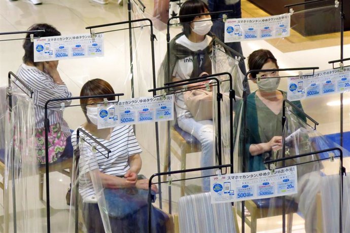 Mujeres con mascarilla haciendo cola para entrar en un centro comercial en Tokio