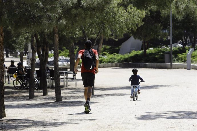 Un hombre hace deporte con un niño en bicicleta por Madrid Río.