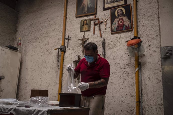 Un empleado del crematorio de San Isidro, en Ciudad de México, prepara las cenizas de una persona que falleció a causa de la COVID-19.