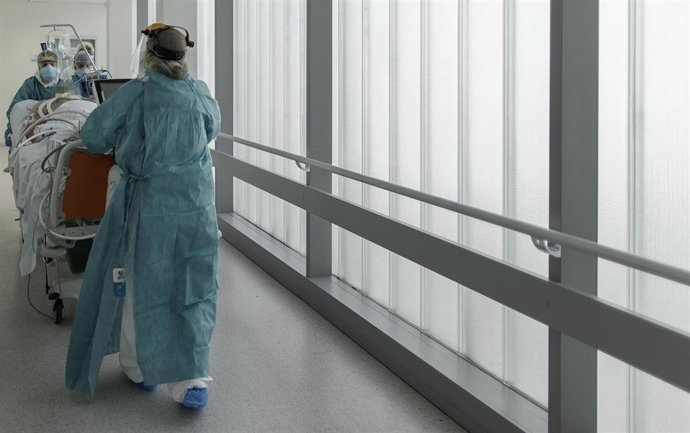 Personal sanitario totalmente protegido trasladan a un paciente (Archivo)