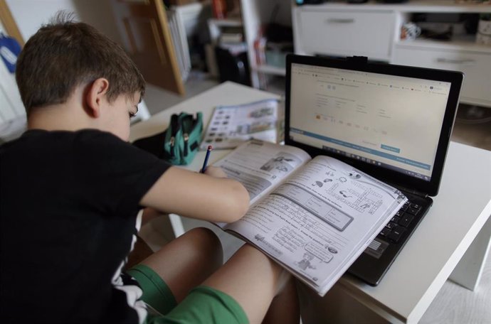 Un alumno de primaria hace los deberes de la asignatura de Inglés con varios libros y un ordenador