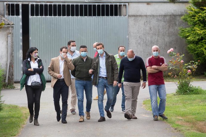 El presidente del PP, Pablo Casado (c), a su llegada para visitar una explotación láctea en compañía de la cabeza de lista por la provincia a las elecciones del 12 de julio, Elena Candia (1i), y del secretario general del PPdeG, Miguel Tellado (2d), ent