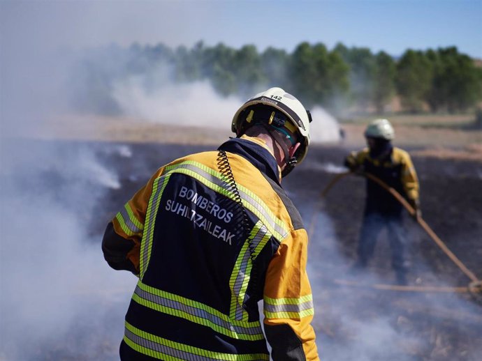 Varios bomberos realizan labores de extinción de un incendio forestal producido en una zona de campo de cereal, sin afectar a zonas urbanas, cerca de la localidad navarra de Sarriguren, a 21 de junio de 2020.