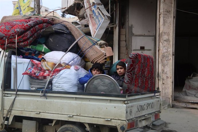 Unos niños sirios en un camión con las pertenencias de su familia huyen de la ofensiva en Idlib
