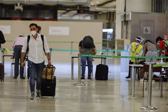 Pasajeros procedentes de Londres rellenan un formulario a su llegada al Aeropuerto de Madrid-Barajas Adolfo Suárez como medida de control.