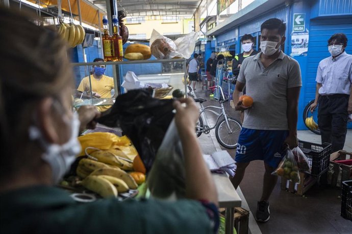 Un hombre hace cola para ser atendido en un puesto de frutas de un mercado de Lima, Perú, durante la pandemia de la COVID-19.