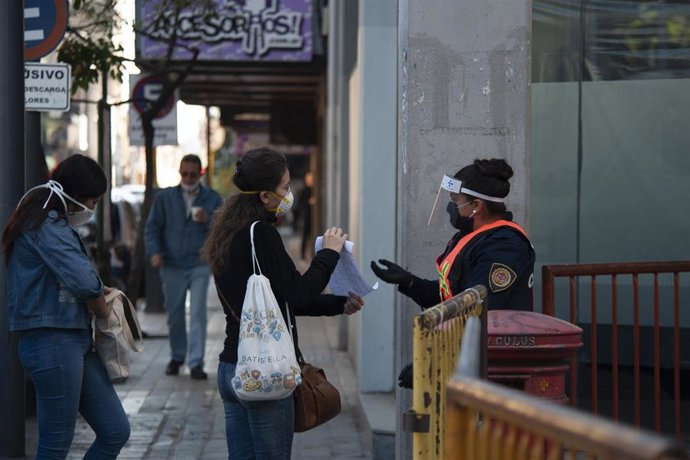 Una agente de la Policía comprueba el permiso de una ciudadana para circular por las calles de Córdoba en medio de las medidas de restricción de movimientos impuestas en Argentina para frenar la COVID-19.