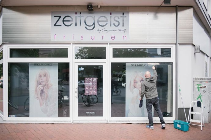 Un trabajador limpia los cristales de una peluquería en Hanover