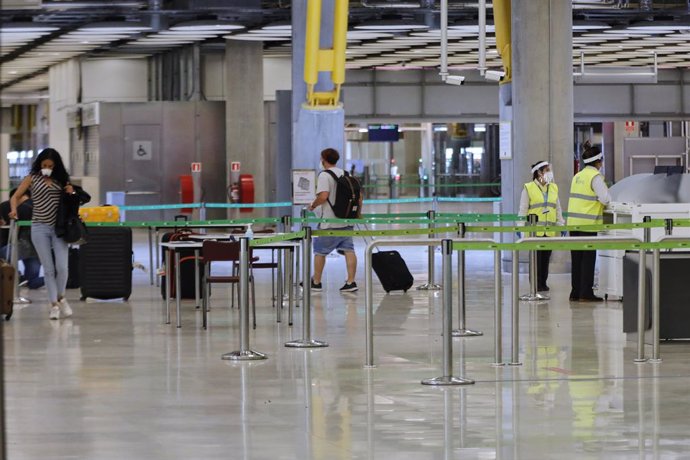 Pasajeros procedentes de Londres caminan entre los pasillos delimitados, antes de rellenar un formulario, a su llegada al Aeropuerto de Madrid-Barajas Adolfo Suárez, como medida de control de los casos sospechosos de coronavirus cuatro días después desd