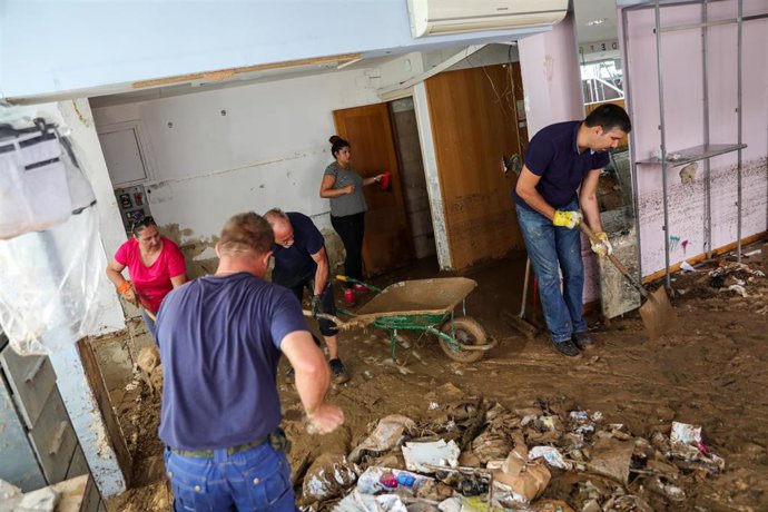 Varios vecinos limpian el suelo embarrado y lleno de basura del interior de un local tras la riada en Arganda del Rey por las lluvias, en Madrid a 16 de septiembre de 2019.