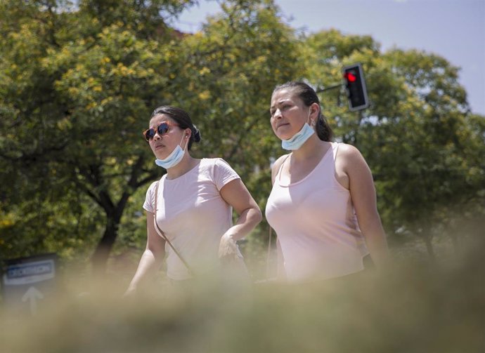 Dos mujeres caminan con la mascarilla bajada durante la alerta naranja por altas temperaturas. En Sevilla (Andalucía, España), a 23 de junio de 2020.
