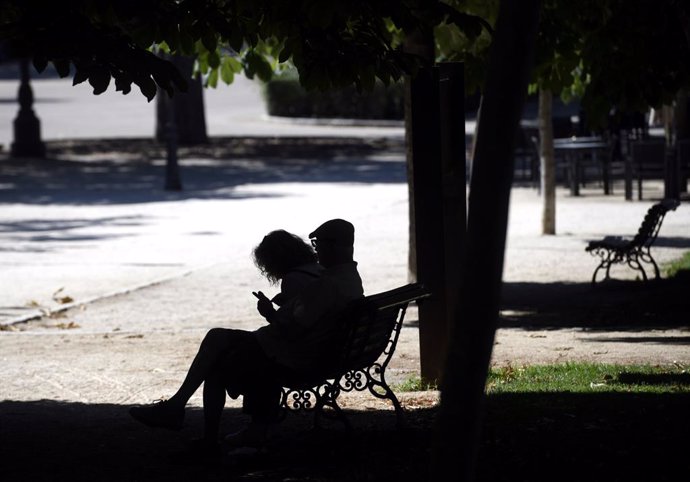 Una pareja sentada en un banco en el Parque del Retiro en Madrid.