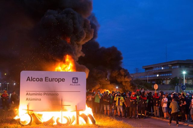 Manifestantes durante una concentración nocturna convocada por el comité de Alcoa San Cibrao, en el entorno de la fábrica de San Cibrao, queman el cartel de la multinacional en Lugo, Galicia (España), a 30 de junio. La manifestación, es una de las tantas 