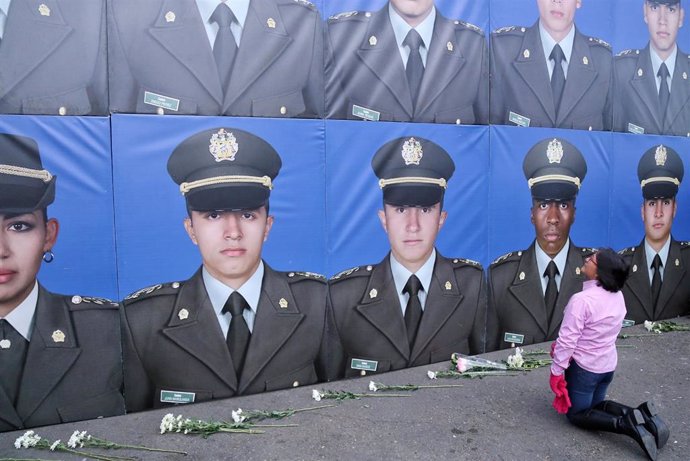 Una mujer se postra ante los retratos de algunos de los reclutas fallecidos  tras el ataque bomba del ELN en la Escuela de Policías General Santander, de Bogotá.