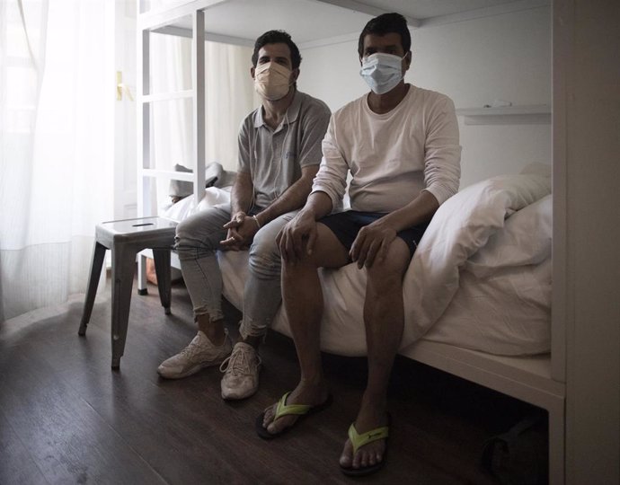 Fernando Cachopo (i) y Mdnadrul Islam (d), posan ante la cámara desde sus habitaciones en el centro situado en la calle Atocha para personas vulnerables habilitado por la Comunidad de Madrid y gestionado por Cruz Roja. Madrid, a 2 de julio de 2020.