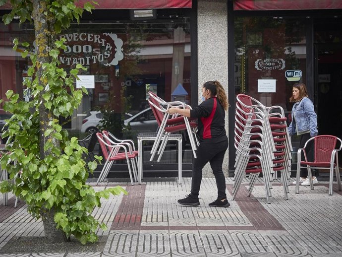 Una camarera prepara la terraza de una Cervecería