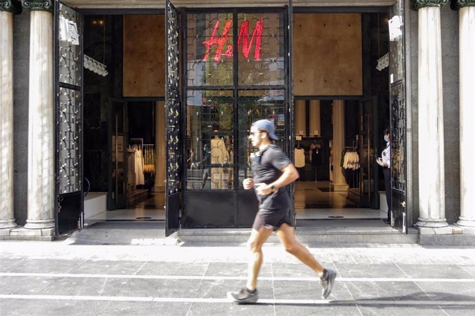 Un hombre pasa corriendo junto a una tienda de moda HyM en la Gran Vía abierta durante la fase 1 de la desescalada en la que se permite reapertura de locales y establecimientos minoristas con una superficie igual o inferior a 400 metros cuadrados