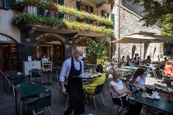 Un camarero sirve a unos clientes en una terraza en Bérgamo, Italia