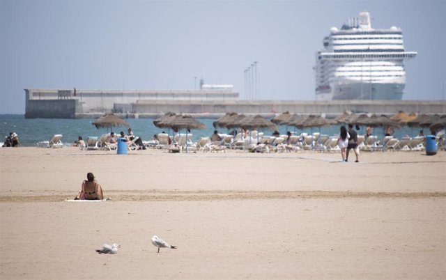 Una mujer descansa en la arena de la playa de la Malvarrosa de Valencia en un soleado día, víspera del inicio del estío