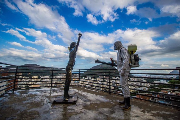 Un operario desinfecta una estatura de bronce situada en la favela de Santa Marta en Río de Janeiro.
