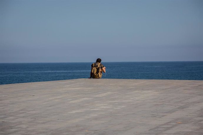 Un joven sentado en el Paseo Marítimo de la Playa de la Barceloneta durante el día 66 del estado de alarma decretado por el Gobierno a causa del Covid-19, en Barcelona/Catalunya (España) a 20 de mayo de 2020.