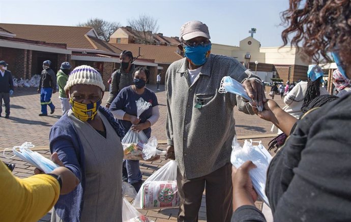 Ciudadanos con mascarilla reciben ayuda durante la pandemia en Soweto