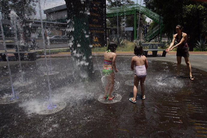 Una familia se divierte jugando con una fuente situada en el Parque de Coyoacan, en Ciudad de México.